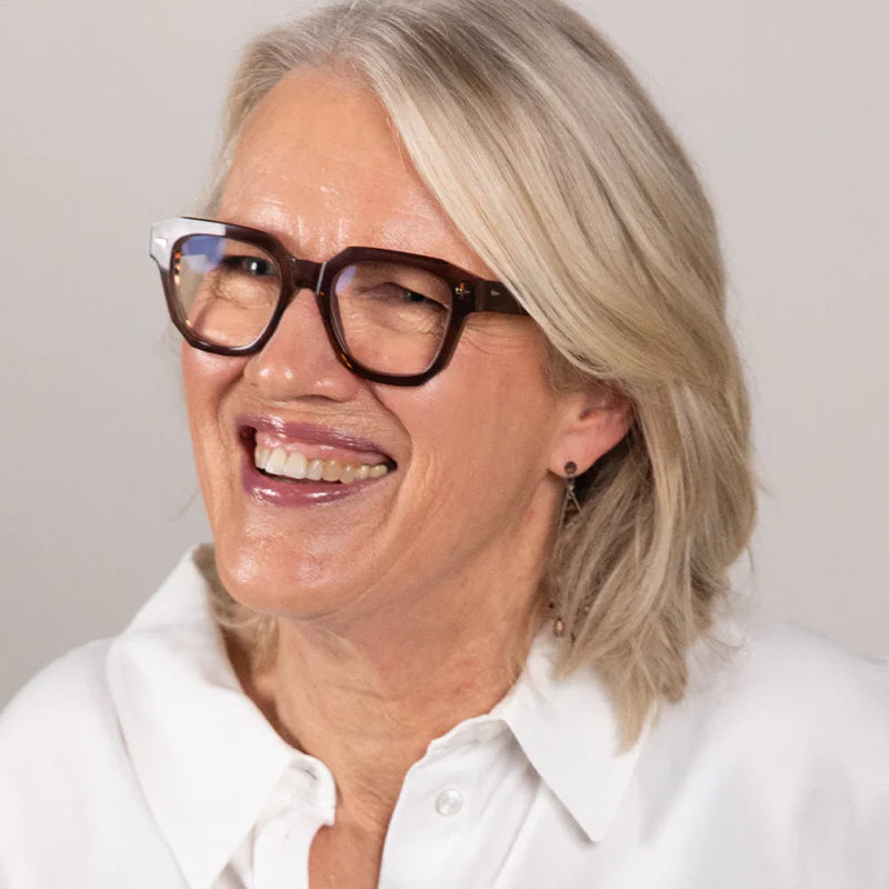 Woman wearing glasses and a white shirt against a plain background