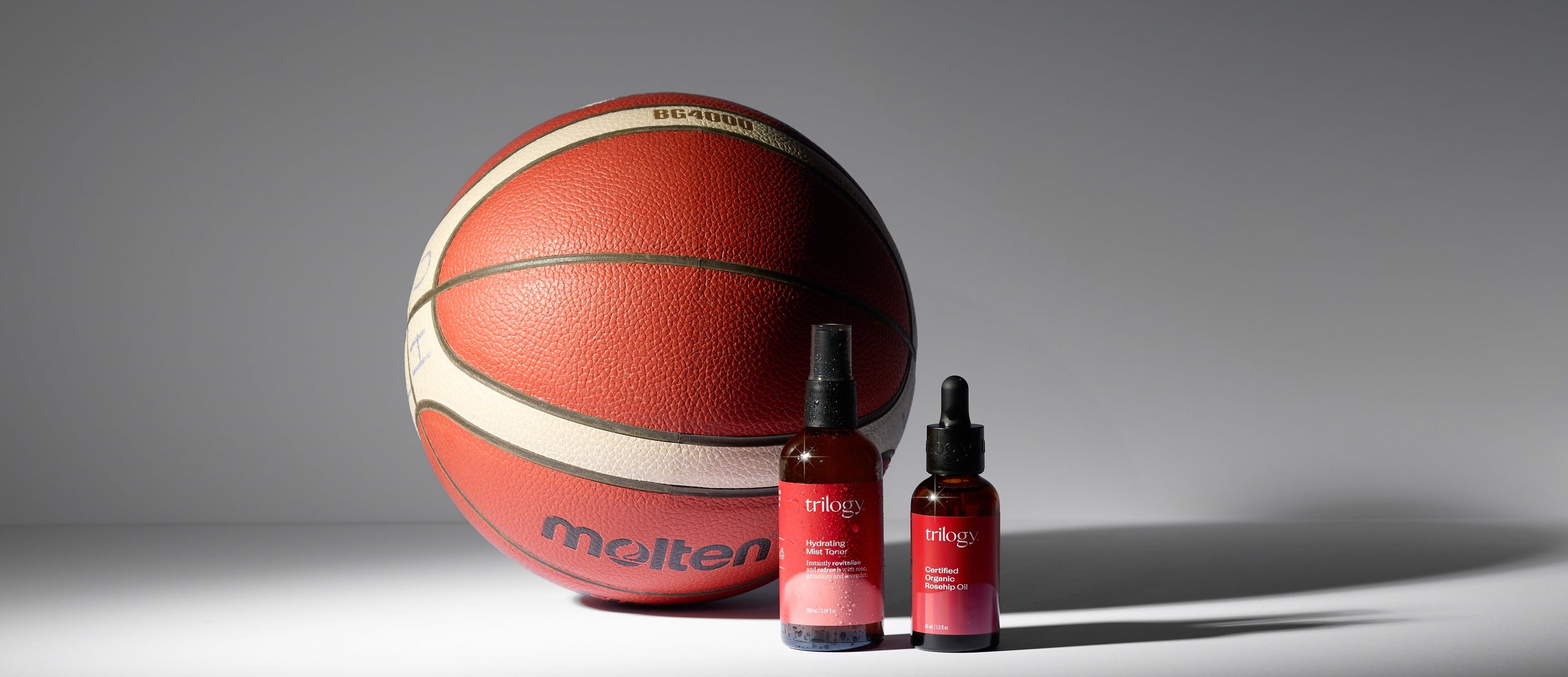 Basketball and two bottles of trilogy skincare on a gray background